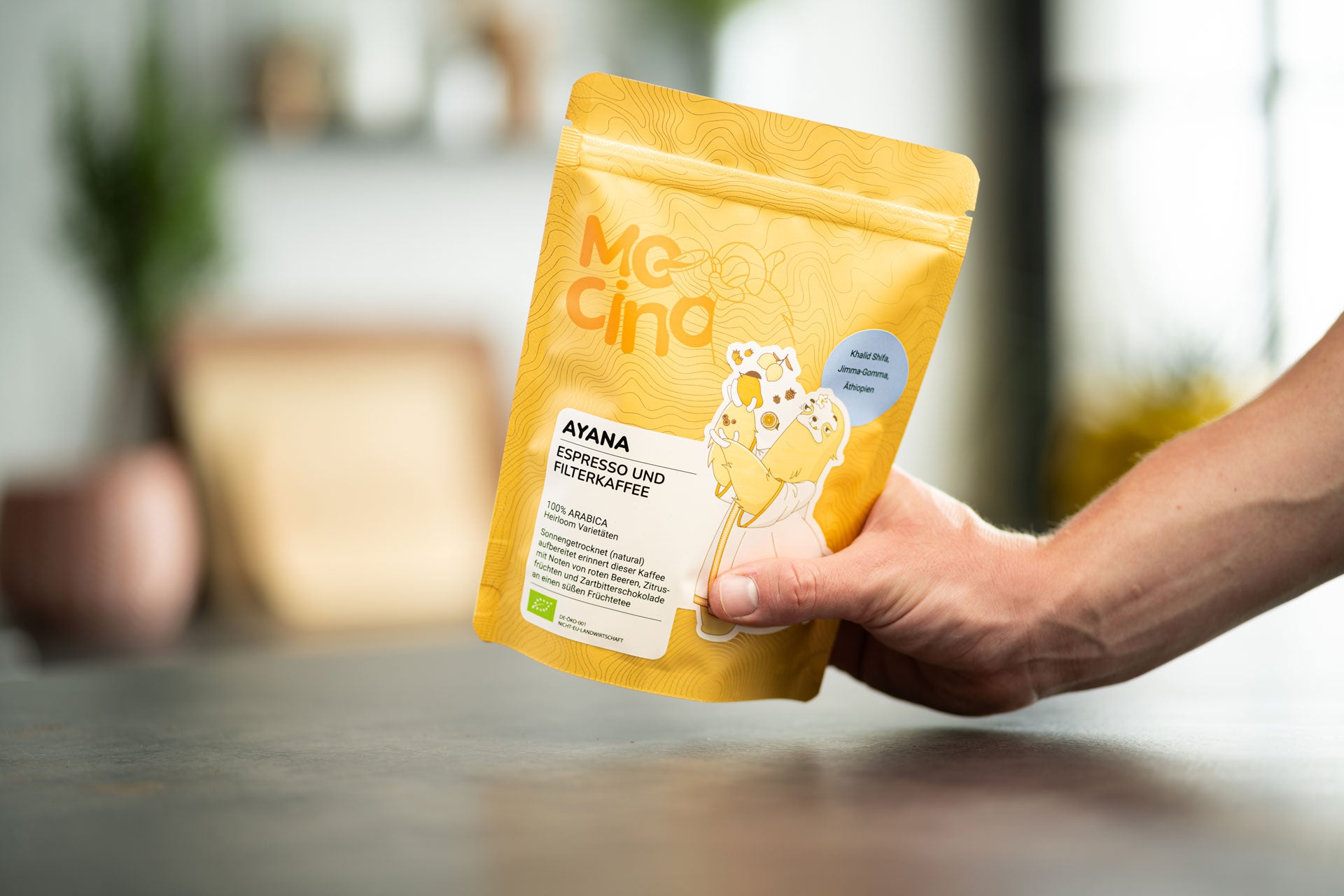 Eine Hand greift nach der Kaffeetüte Ayana von Mocino in einer modernen Küche