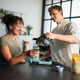 Zwei Menschen trinken einen Kaffee von Mocino aus einer türkisen Moccamaster 