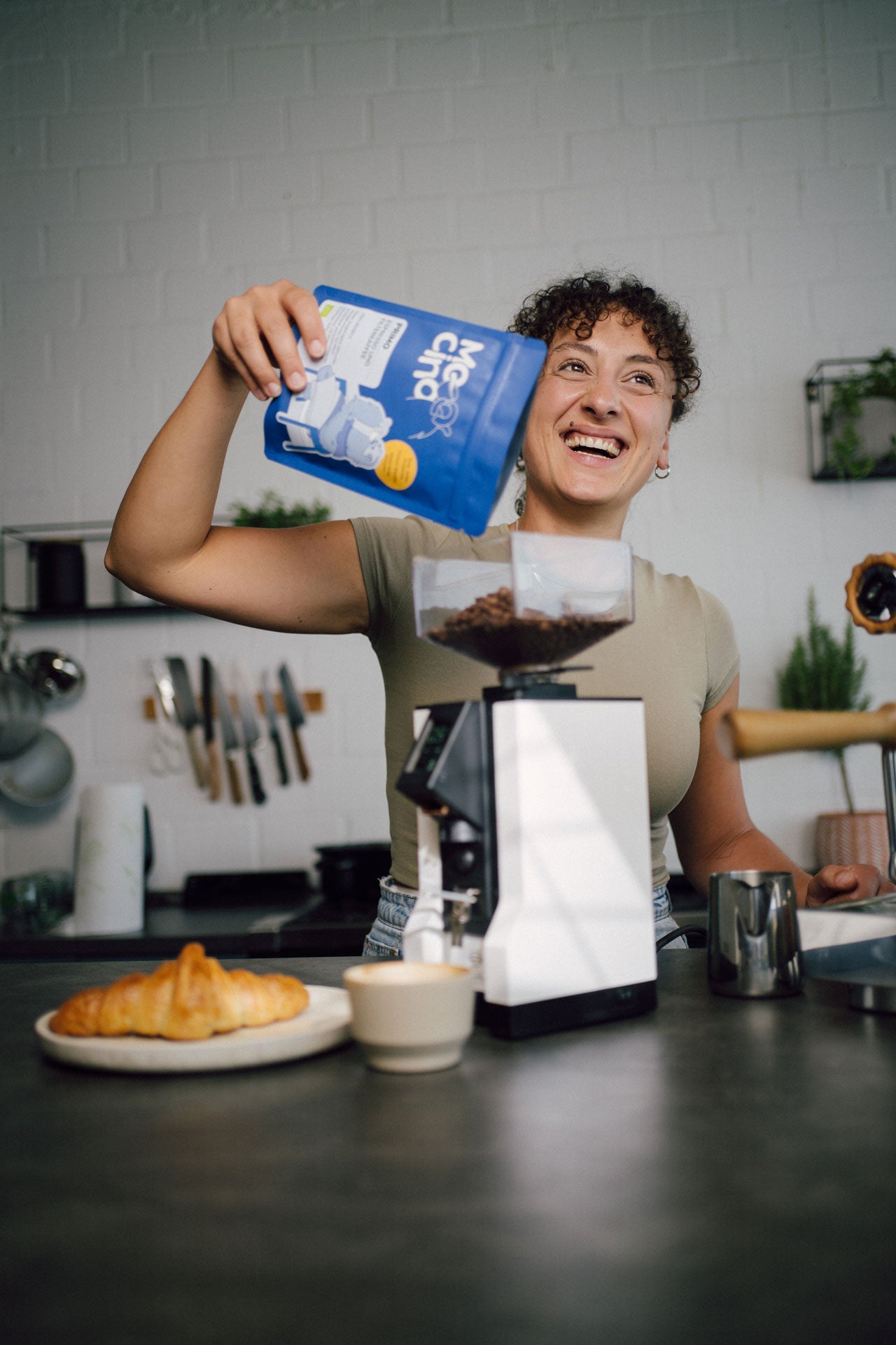 Eine Frau schüttet den Kaffee PRIMO in die Espressomühle in einer Küche